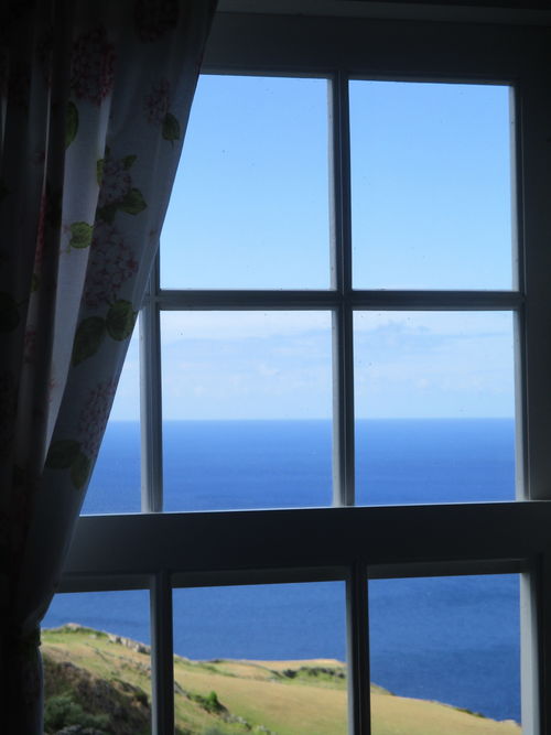 campo, mar y cielo vistos a través de una ventana tradicional de madera