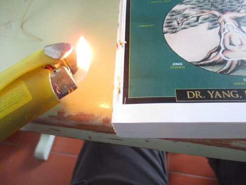 quemando extremo final de hilos que juntan pliegos de libro casero