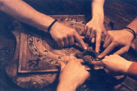 Cuatro manos manejando una tabla Ouija